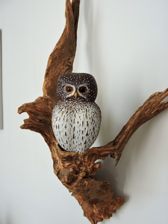 Pygmy owl, a sculpture of an owl sitting on a branch, carved owl, Glaucidium passerinum.